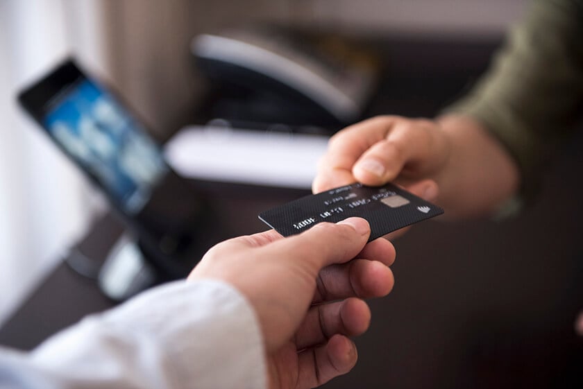 shopper handing over credit card shopper handing over credit card with screen and phone in the background
